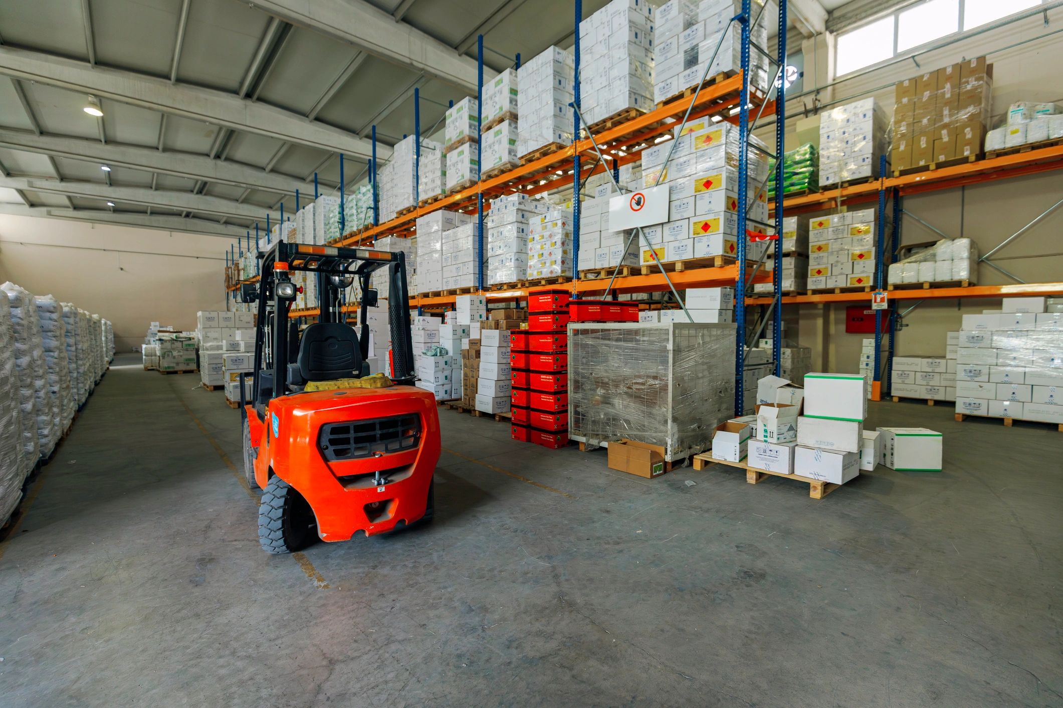 Warehouse aisle with forklift and stacked goods